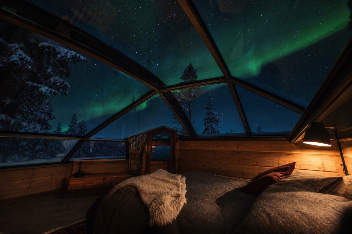 A glass-roofed igloo cabin under an Arctic night sky