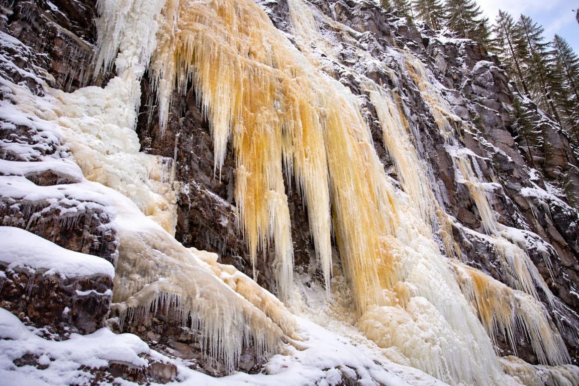 Frozen Ruskea Virta waterfall with golden ice formations in Korouoma Canyon near Rovaniemi, captured during a guided tour with Rovaniemi Tours